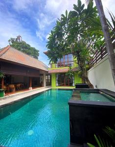 una piscina frente a un edificio con árboles en Villa Mudha 3 Sanur, en Sanur