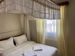 Una cama con dos toallas junto a una ventana. en Easy Sleep Guesthouse, en Kitale