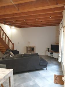 uma sala de estar com um sofá preto e um tecto de madeira em Gîte l'olivier em Mézoargues