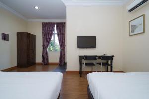 a room with two beds and a desk and a television at Super OYO 90009 Bangi Sri Minang Guesthouse in Bangi
