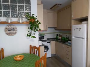 a kitchen with a table and a white refrigerator at Verdemar Apartamento Bajo in Peñíscola