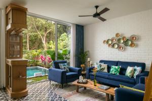 a living room with a blue couch and chairs at La Avila by The Blue Kite - 2 BHK Villas near Morjim Beach & Thalassa with Private Pool, Kitchen, Balcony & Security in Siolim