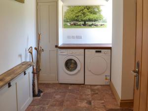 a laundry room with a washing machine and a window at Court Barn in Buckerell