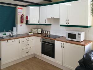 a kitchen with white cabinets and a microwave at Bullrushes in Horning