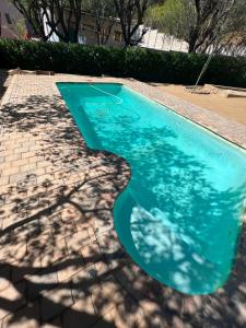 a swimming pool with a shadow of a tree at Chateau du Windhoek in Windhoek