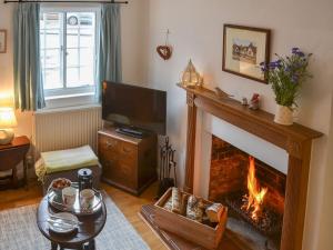 a living room with a fireplace and a tv at Lavenham Red Brick Cottage in Lavenham