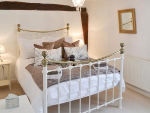 um quarto com uma cama branca com almofadas em Lavenham Red Brick Cottage em Lavenham