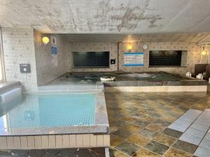 - une grande piscine dans un bâtiment dans l'établissement カプセル&サウナ日本 -男性専用 men only-, à Fukuyama