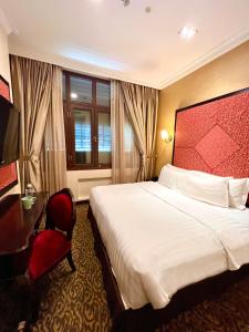 シンガポールにあるNostalgia Hotelの大きなベッドとデスクが備わるホテルルームです。