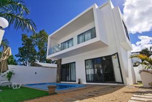 uma casa branca com uma piscina em frente em villa de la lumiere em Trou-aux-Biches