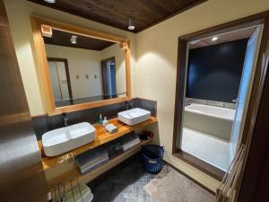 a bathroom with two sinks and a large mirror at Akari House Swiss Bakery in Nozawa Onsen