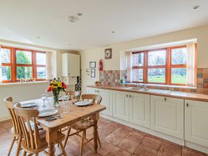 a kitchen with a table and chairs and a kitchen with windows at The Parlour - Uk37517 in Routh