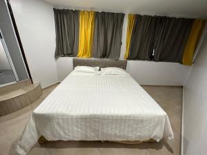 un letto bianco in una stanza con due finestre di Hotel Uptown Semenyih a Semenyih