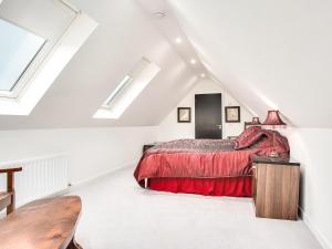 a attic bedroom with a red bed and skylights at The Old Barn - Uk40948 in Auchtermuchty