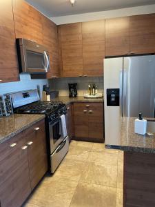 a kitchen with wooden cabinets and a stainless steel refrigerator at Villa Marina - Modern & Immaculate, Spacious, Gated Condo with Fireplace Pool, Gym, 2 Master Bedrooms in Los Angeles