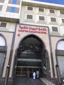 Twee mannen lopen een gebouw binnen met een bord erop. bij Al Rayyan Towers 4 in Mekka