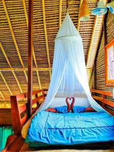 a bed in a room with a mosquito net at Cute Eco Cottage Near 7 Waterfalls in Singaraja