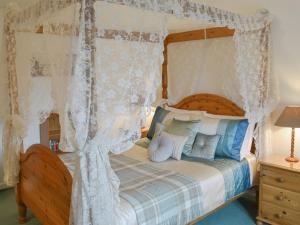 - une chambre avec un lit à baldaquin et des rideaux blancs dans l'établissement Grannys Cottage, à Lostwithiel