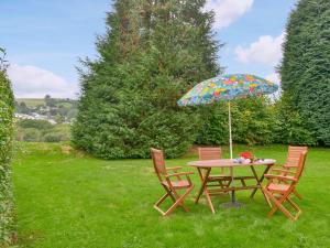une table et des chaises avec un parasol dans l'herbe dans l'établissement Grannys Cottage, à Lostwithiel