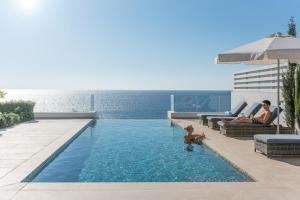 a man and a woman sitting in a swimming pool at Cap St Georges Villas in Peyia