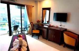 ein Wohnzimmer mit einem TV und einem Schreibtisch mit einem Tisch in der Unterkunft Aya Place in Pattaya South