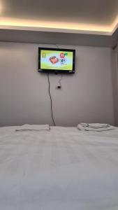 telewizor z płaskim ekranem wiszący na ścianie obok łóżka w obiekcie Studio Albert w mieście Râmnicu Vâlcea