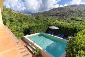 una piscina con sombrilla y 2 sillas en Holiday home in Francavilla di Sicilia, en Francavilla di Sicilia