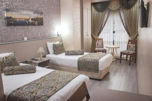 um quarto de hotel com duas camas e uma mesa e cadeiras em Elite Marmara Gungoren em Istambul