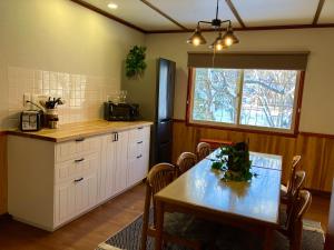 eine Küche mit einem Tisch, einem Tisch und einem Fenster in der Unterkunft Lodge Blue Mount Hakuba in Hakuba