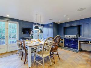 cocina con armarios azules, mesa y sillas en Anchor Light Cottage en Faversham