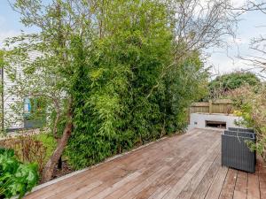 un gran árbol verde en una pasarela de madera en Anchor Light Cottage, en Faversham