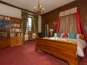 um quarto com uma cama e uma estante de livros em Hockwold Hall em Hockwold cum Wilton