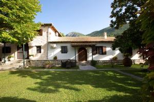 une grande maison blanche avec une cour en herbe dans l'établissement Villagio Magnolia, à Sívros