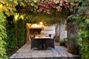 patio ze stołem i krzesłami pod łukiem z kwiatami w obiekcie Villagio Magnolia w mieście Sívros