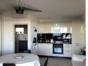 a kitchen with white cabinets and a table with a white table cloth at Sainte Maxime Vue féerique piscine chauffée in Sainte-Maxime