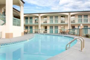 a pool in front of a hotel with tables and chairs at Baymont by Wyndham Gallatin in Gallatin