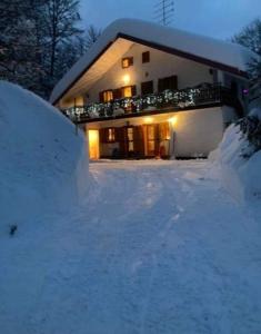 uma casa com um monte de neve em frente em Residenze Ca del bosco Piancavallo em Piancavallo