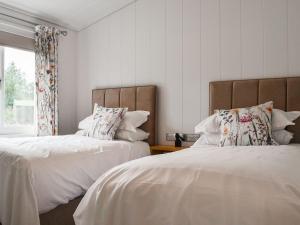 a bedroom with two beds with white sheets and a window at The Alpaca Lodge in Arlecdon