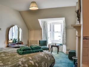 a bedroom with a bed and chairs and a window at St Enodoc in Ullapool