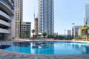 a large swimming pool in a city with tall buildings at The Smart Concierge - Damac Waves in Dubai