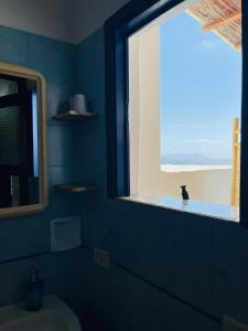 a blue bathroom with a window and a toilet at Perla Salina in Leni