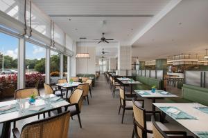 a dining room with tables and chairs and windows at Yuehua Hotel Xiamen Seaside Hotel in Xiamen