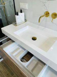 um lavatório branco com uma torneira dourada em Siauliai ‘Four sisters’ em Siauliai