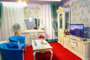 a living room with a tv and a blue chair at Dendi Plaza Hotel in Bukhara