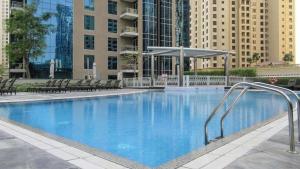a large swimming pool with chairs and buildings at Attessa Tower, Marina Promenade, Dubai Marina - Mint Stay in Dubai
