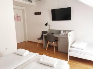 a white bedroom with a desk and a bed and a chair at Rooms Sincere 1830 in Ljubljana