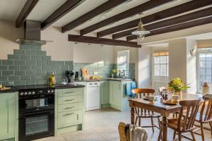 a kitchen with green cabinets and a table with chairs at Garth Cottage in West Ayton in Scarborough