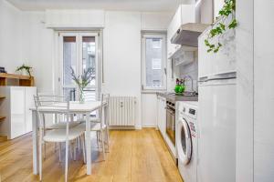 a white kitchen with a table and a stove at ALTIDO Warm and Inviting flat with balcony in Milan