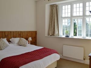 um quarto com uma cama e duas janelas em The Farmhouse em Holwell