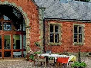 a table and chairs in front of a brick building at Talbot Lodge in Ingestre